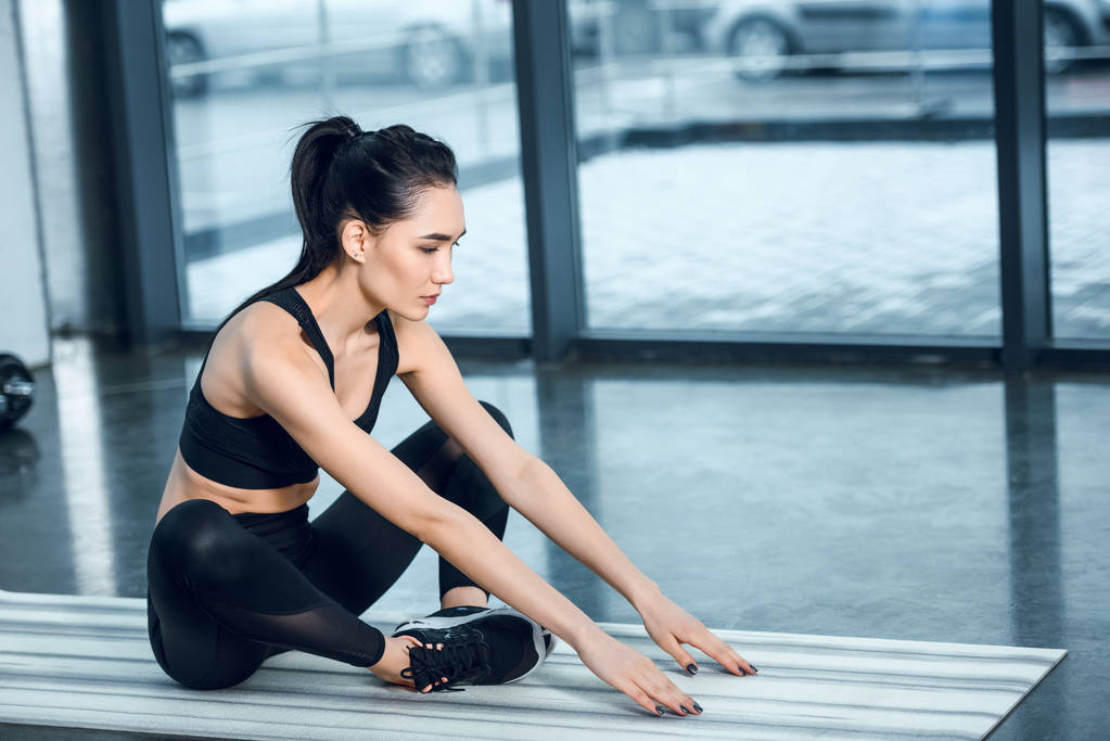 jeune femme athlétique étirant sur tapis de yoga à la salle de gym
 - Photo, image