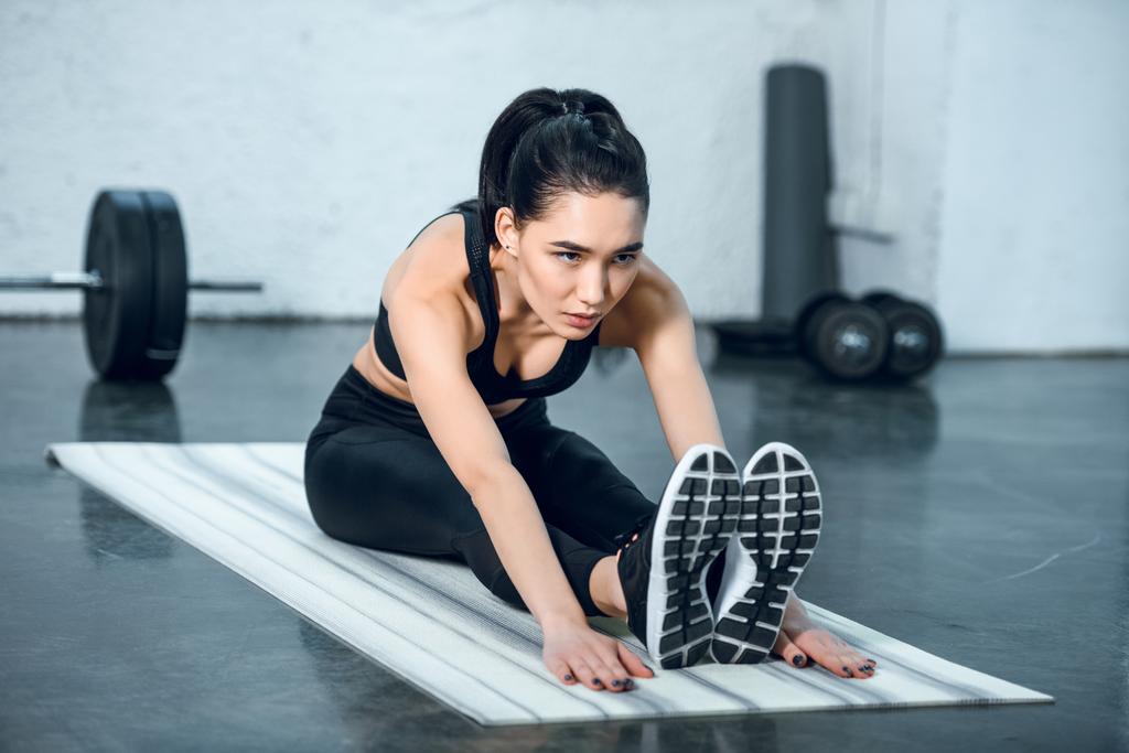 jeune femme sportive faisant courber vers l'avant sur tapis de yoga à la salle de gym
 - Photo, image