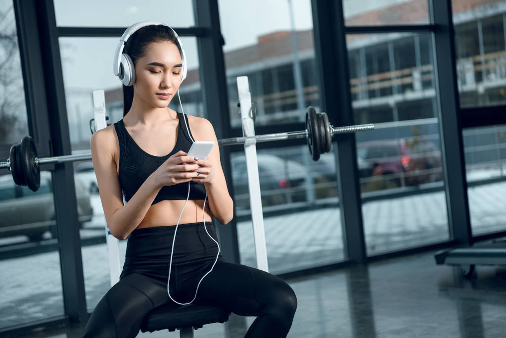 jovem mulher em forma relaxante no ginásio e ouvir música com fones de ouvido
 - Foto, Imagem