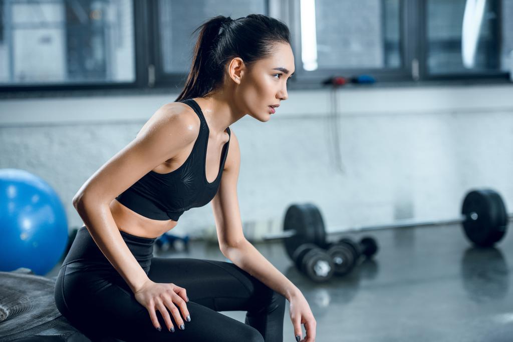 oldalnézetből a vonzó fitt nő ül a kerék workout tornateremben edzés után - Fotó, kép