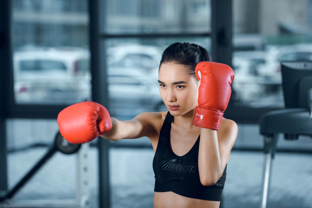 jonge vrouwelijke bokser in handschoenen maken van warmte op sportschool - Foto, afbeelding