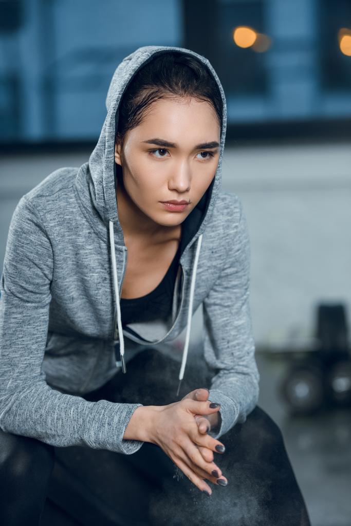 молодая женщина, хлопающая в ладоши тальком перед тренировкой в спортзале
 - Фото, изображение