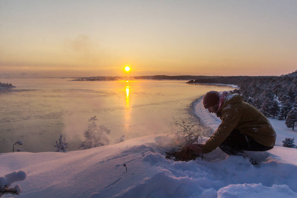tourist on the mountain top warming his hands by the fire. Karelia. Lake Ladoga - Photo, Image