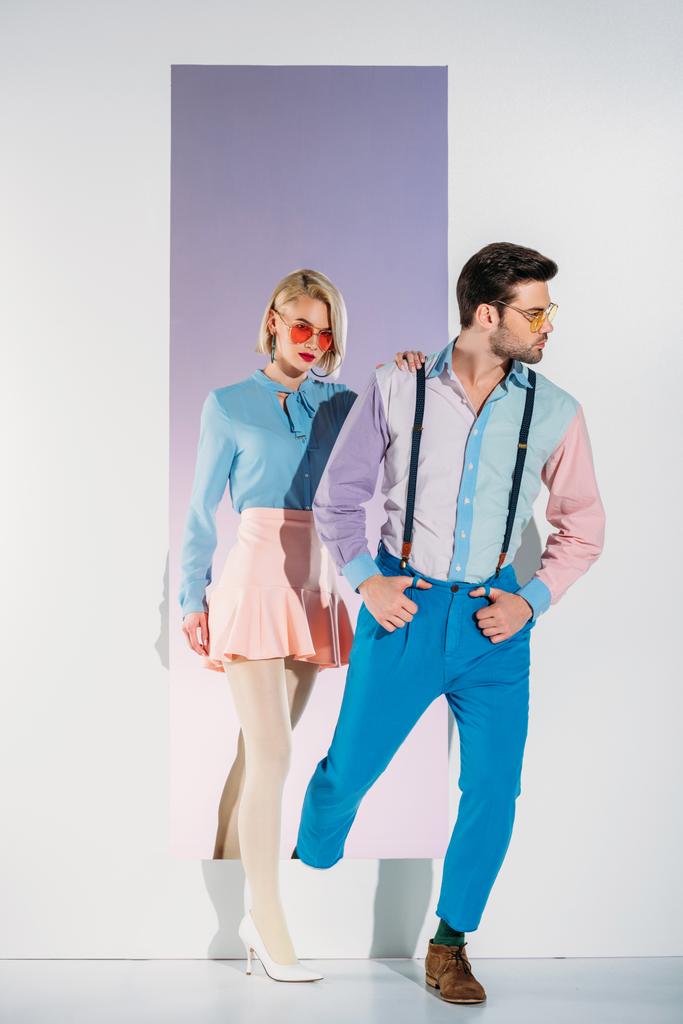 atractiva pareja en ropa de moda pasando por el marco en blanco
 - Foto, Imagen