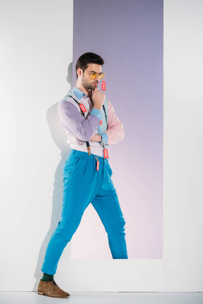 Satılık ile şık giysiler içinde yakışıklı adam ayakta beyaz çerçeve etiketleri - Fotoğraf, Görsel
