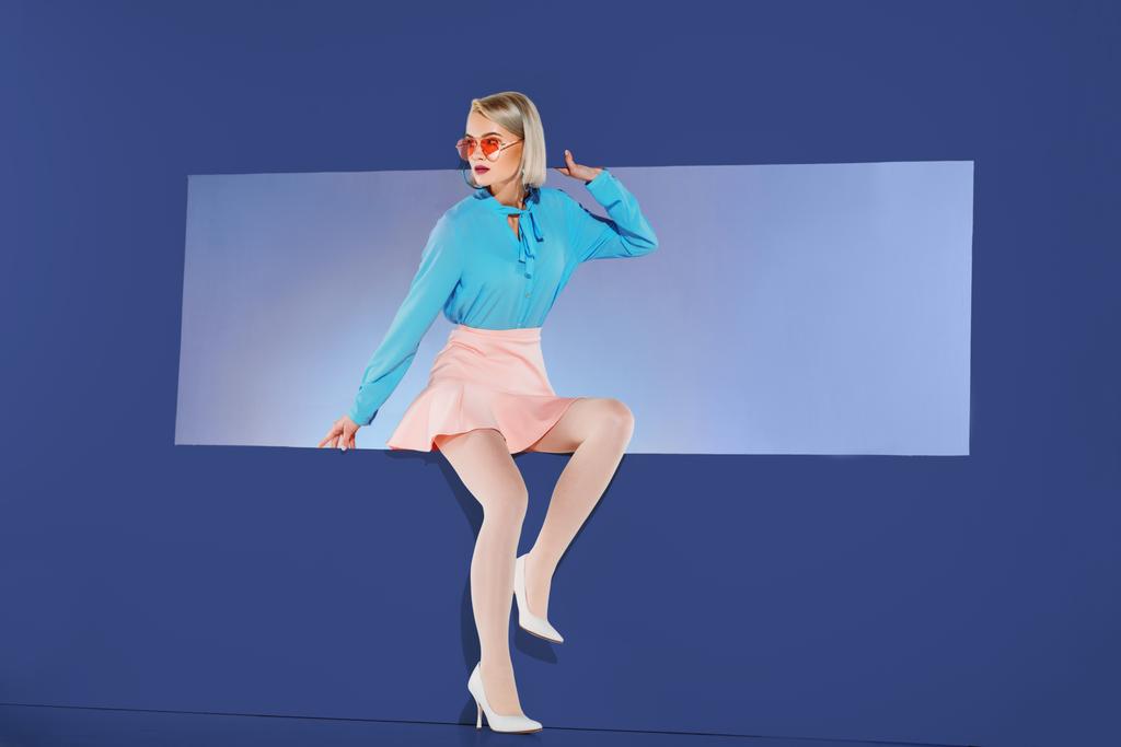 houkutteleva tyttö trendikkäitä vaatteita istuu aukon eristetty sininen
 - Valokuva, kuva