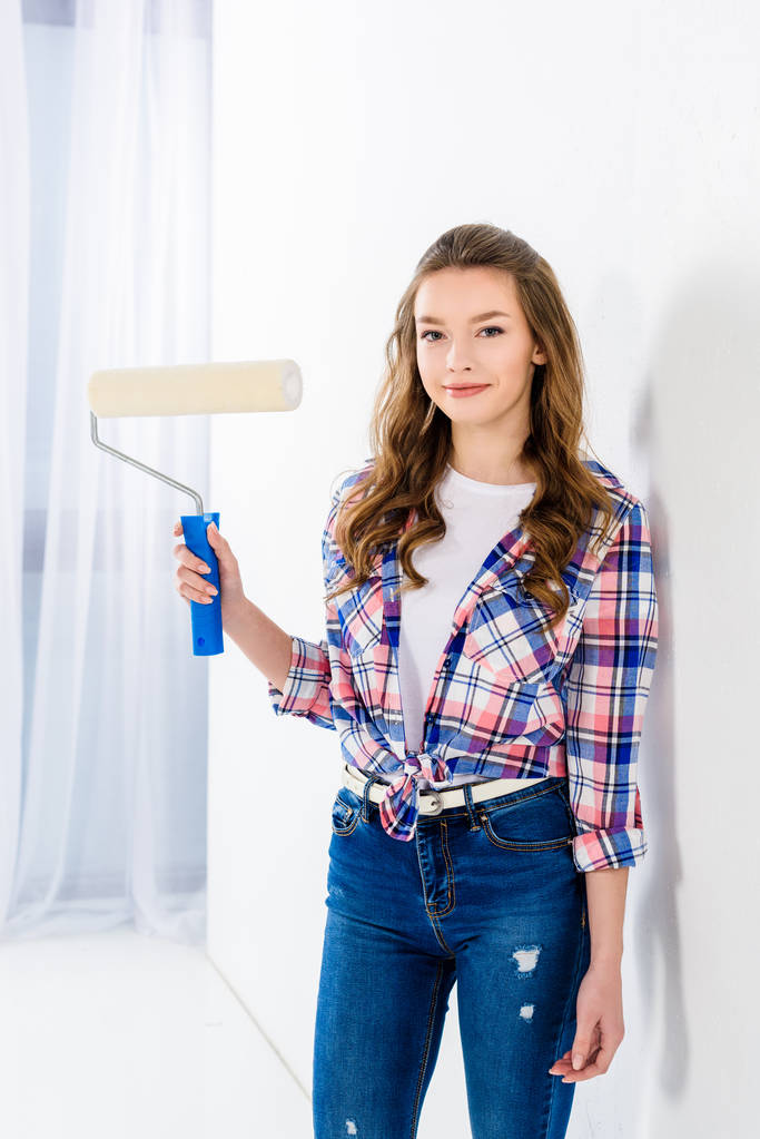 smiling girl holding paint roll brush and looking at camera - Photo, Image