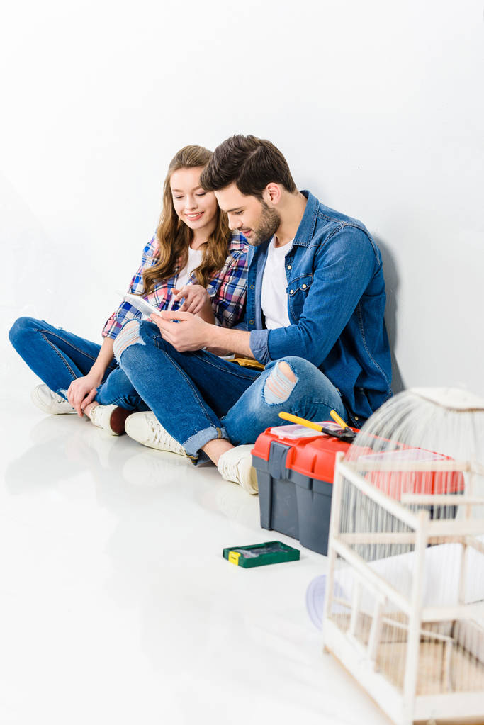 smiling couple sitting on floor and using tablet - Photo, Image