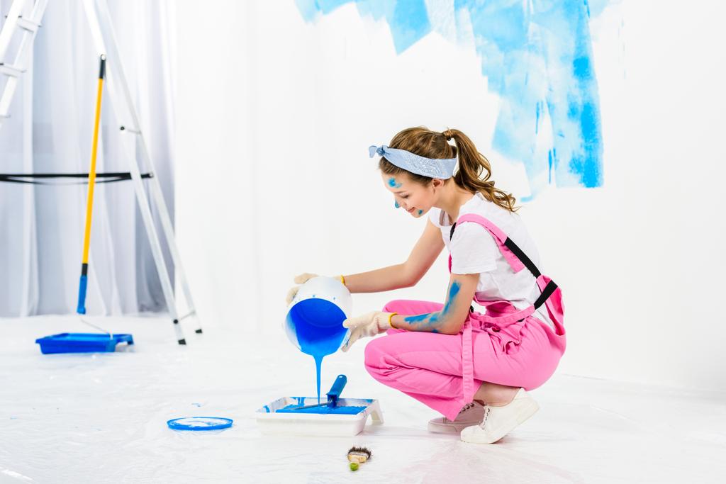 дівчина наливає фарбу з відра в пластиковий лоток для фарби
 - Фото, зображення