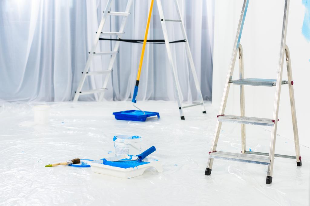 ladders en verf borstelrollen in blauwe verf op kamer - Foto, afbeelding