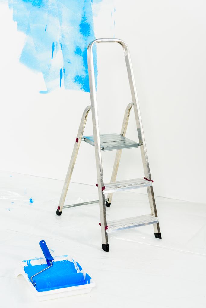 escalera y pincel rodillo de pintura en pintura azul
  - Foto, imagen
