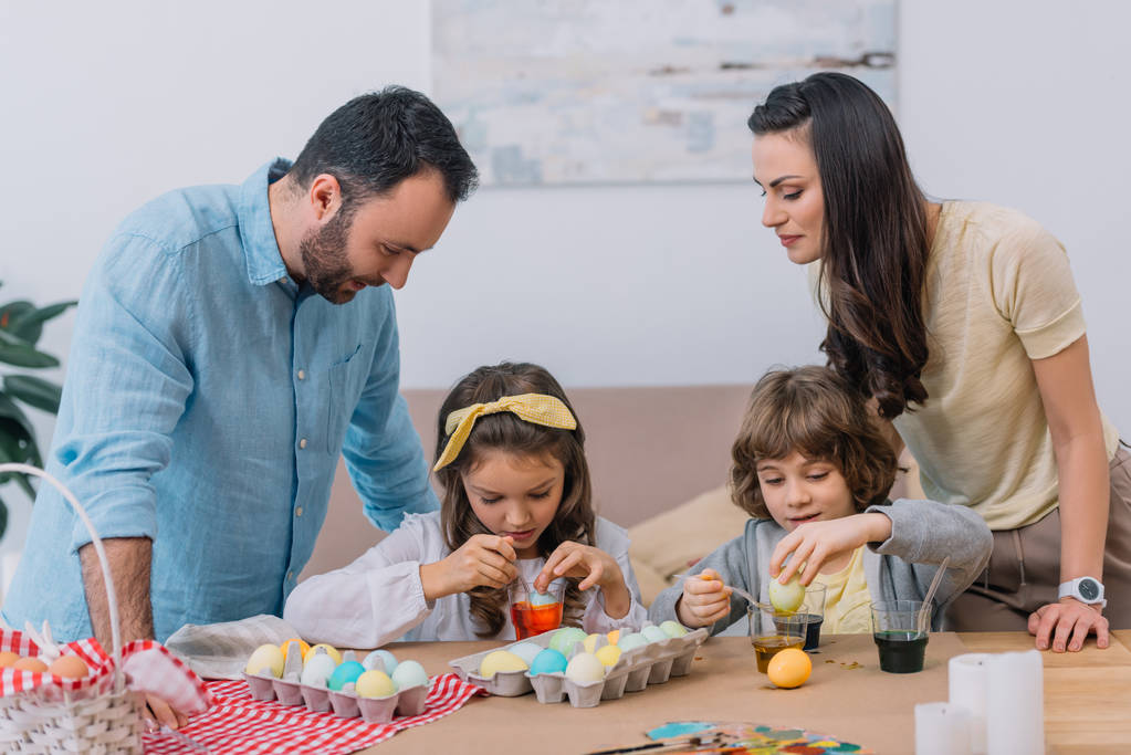 feliz familia joven pintando huevos para pascua en casa
 - Foto, Imagen
