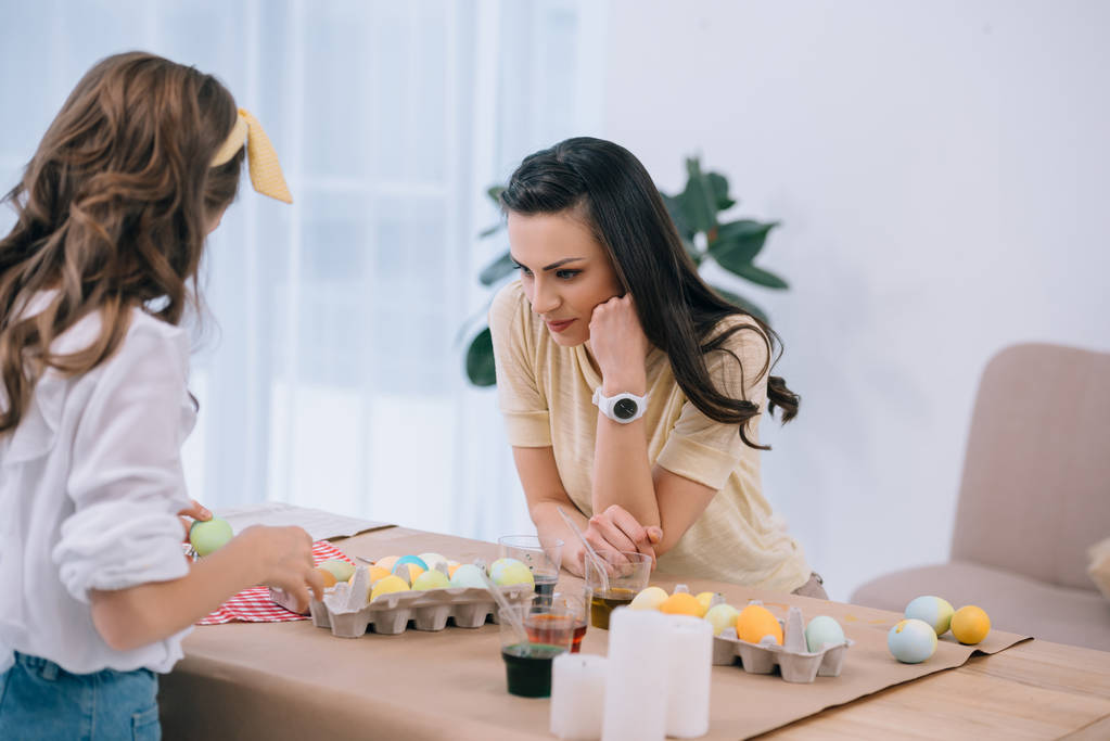 attractive young mother and daughter painting easter eggs together - Photo, Image