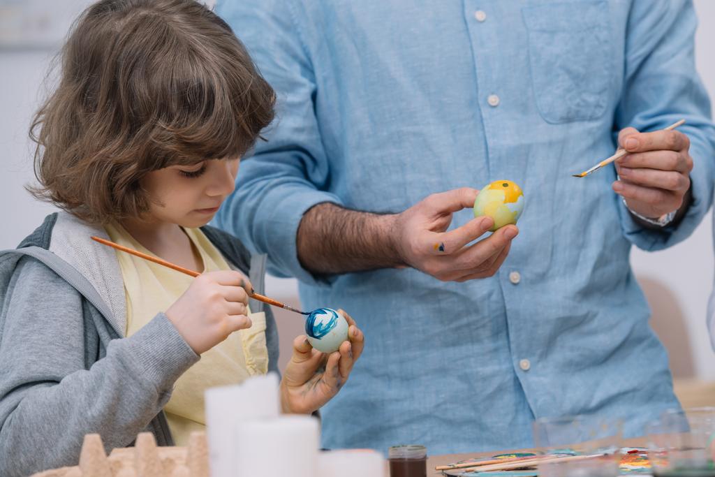 adorable petit enfant peignant des œufs de Pâques avec père
 - Photo, image