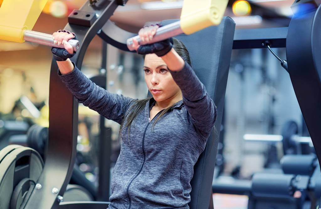 vrouw buigzame spieren op borst druk op gym machine - Foto, afbeelding