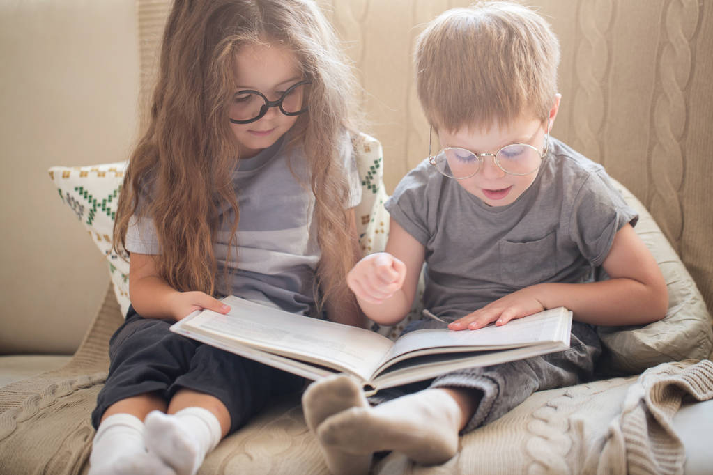 Μικρό αδελφό και αδελφή διαβάζοντας ένα βιβλίο στον καναπέ - Φωτογραφία, εικόνα