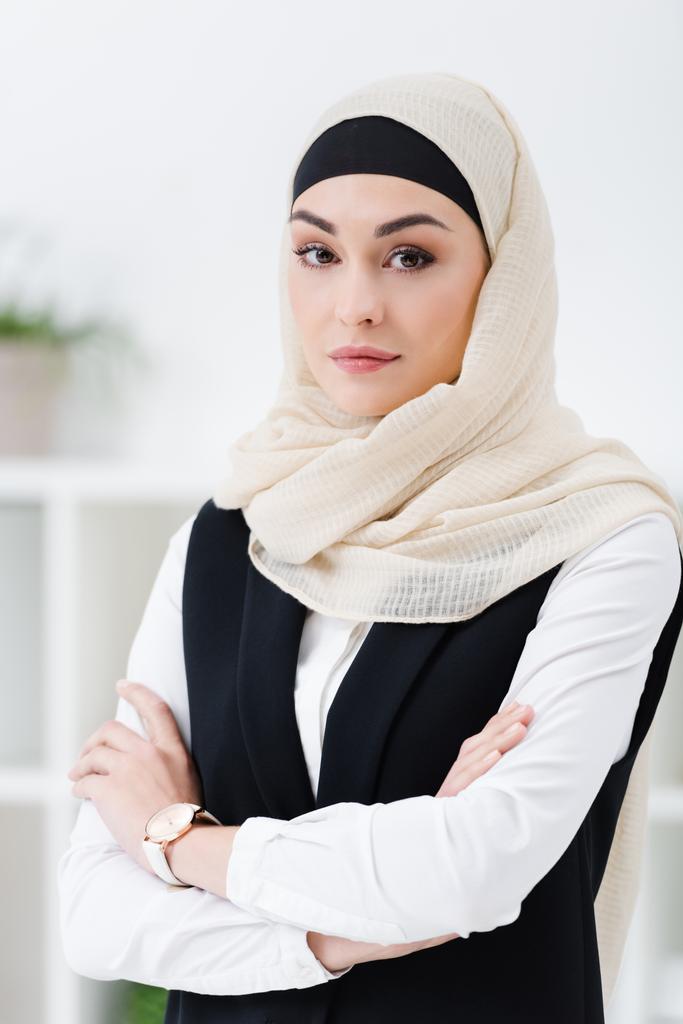 retrato de mulher de negócios árabe no hijab com os braços cruzados de pé no escritório
 - Foto, Imagem
