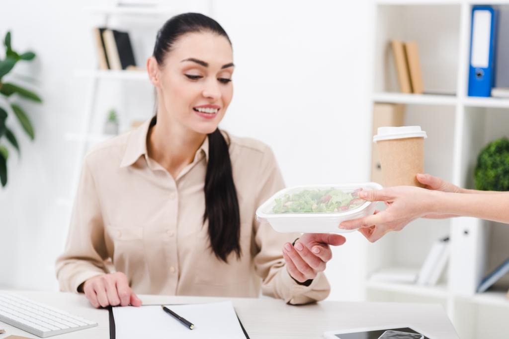 retrato de una mujer de negocios sonriente que le quita comida al mensajero en la oficina
 - Foto, imagen