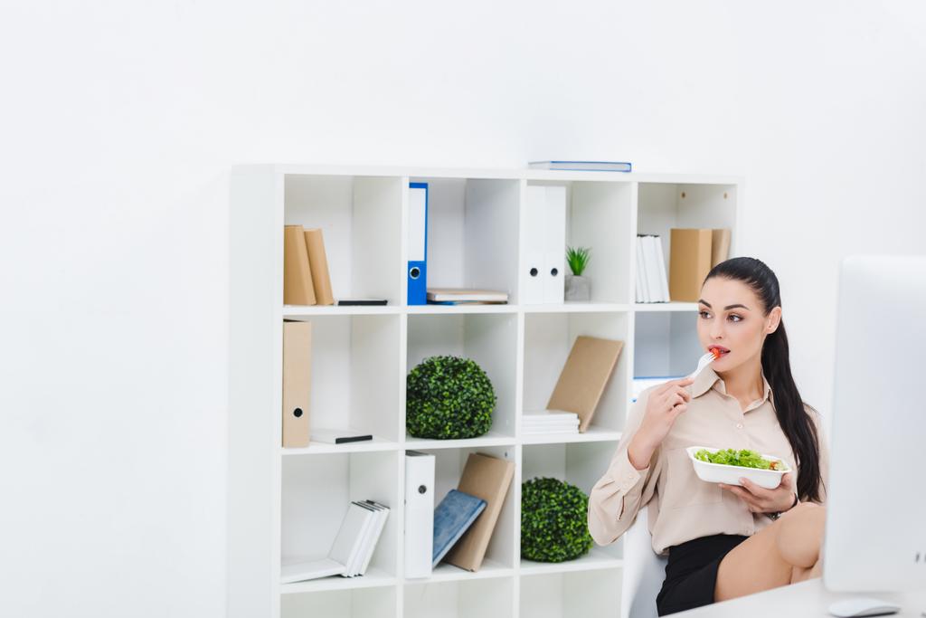 Portret van zakenvrouw take away salade eten voor de lunch op werkplek op kantoor - Foto, afbeelding