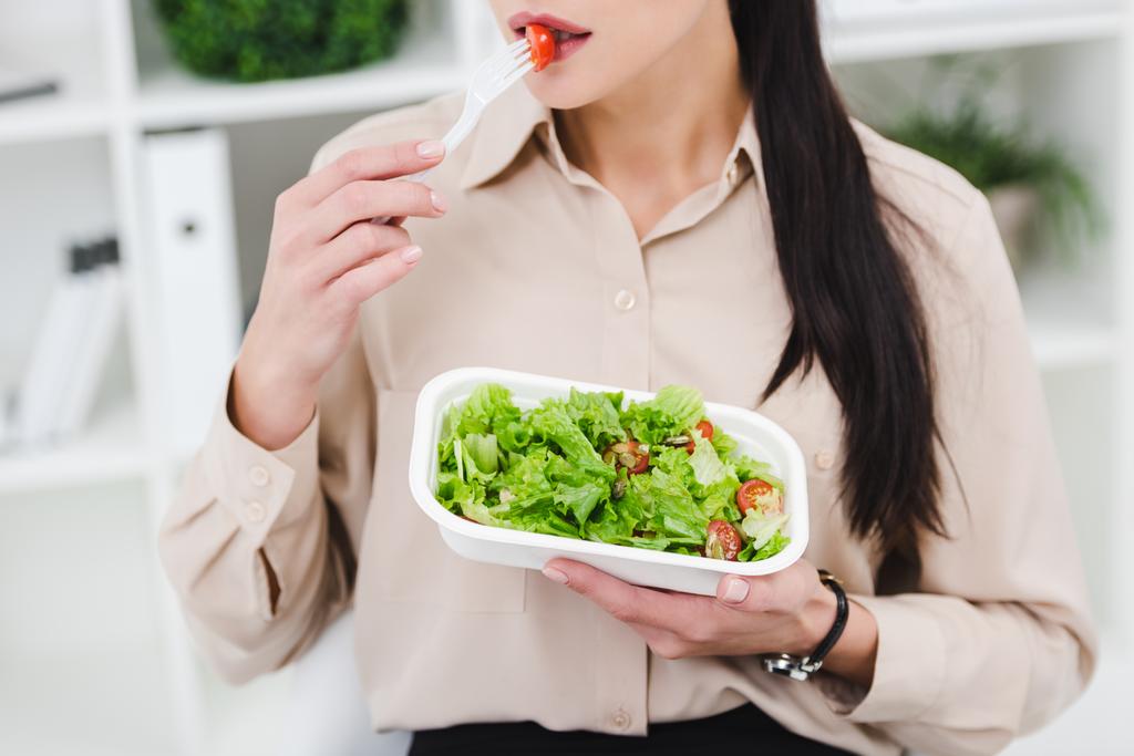 partial view of businesswoman eating take away salad for lunch in office - Photo, Image