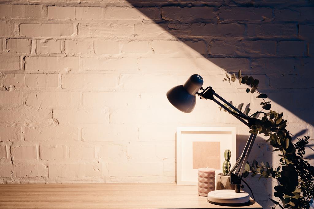 table lamp illuminating white empty brick wall, mockup concept - Photo, Image