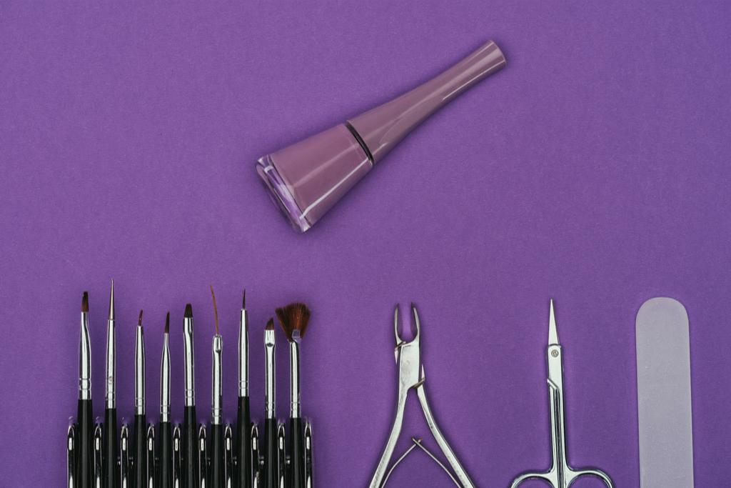 верхний вид лака для ногтей и маникюра инструменты изолированы на фиолетовый
 - Фото, изображение
