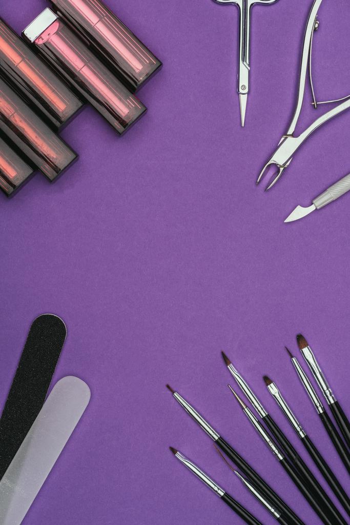 top view of lipsticks and manicure tools isolated on purple - Photo, Image