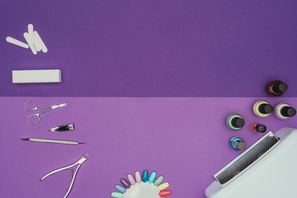 vista superior de herramientas de manicura y lámpara ultravioleta en mesa púrpura
 - Foto, imagen
