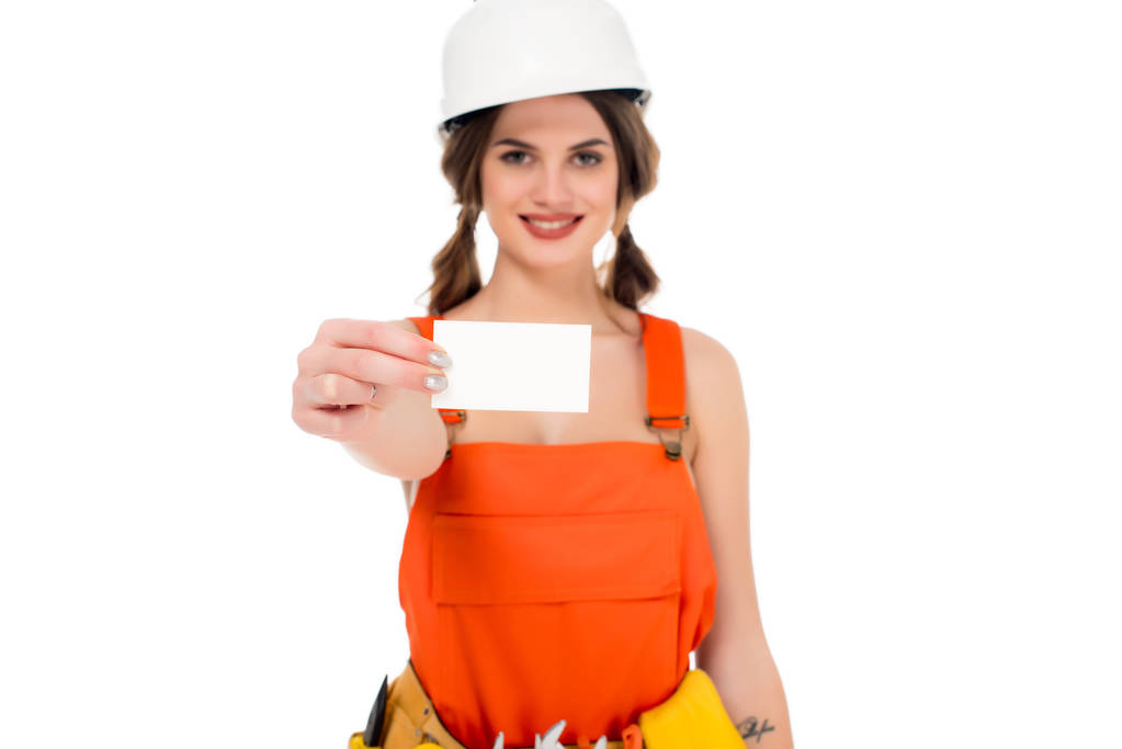 na białym tle uśmiechnięty workwoman w mundurze i hardhat gospodarstwa wizytówkę, - Zdjęcie, obraz