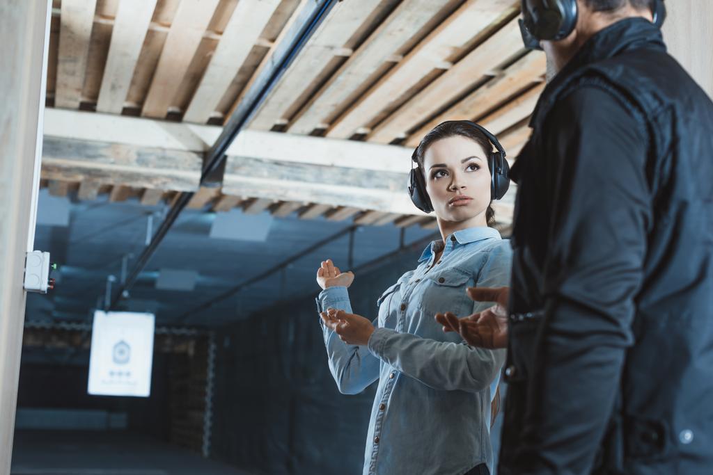 cliente femenino hablando con instructor masculino en rango de tiro
  - Foto, Imagen