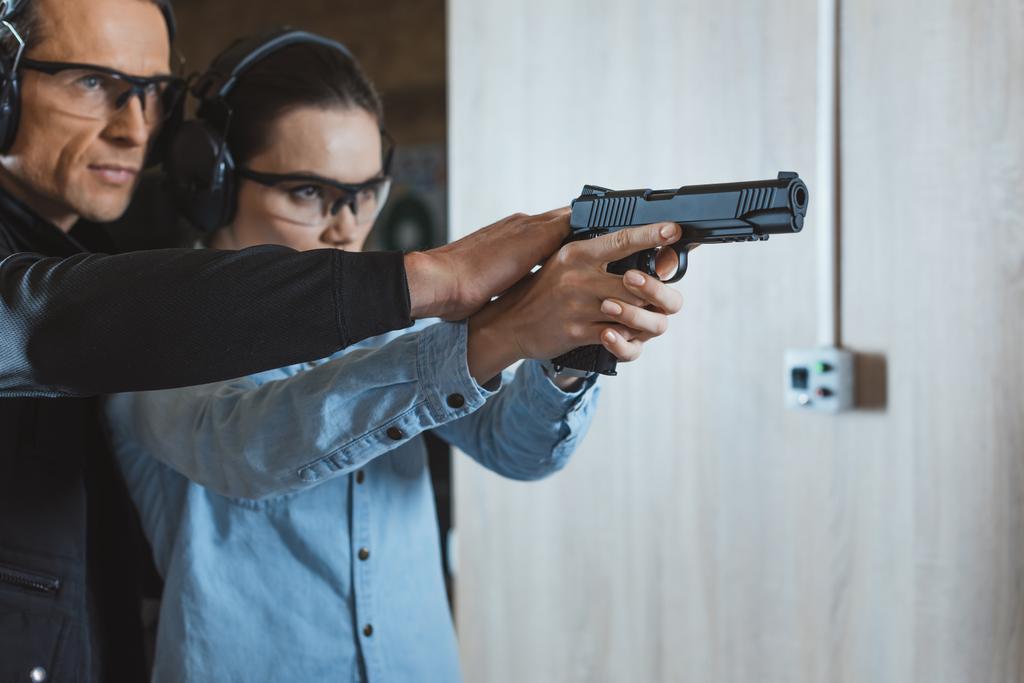男性講師の射撃場で銃を持って撮影する顧客を支援 - 写真・画像