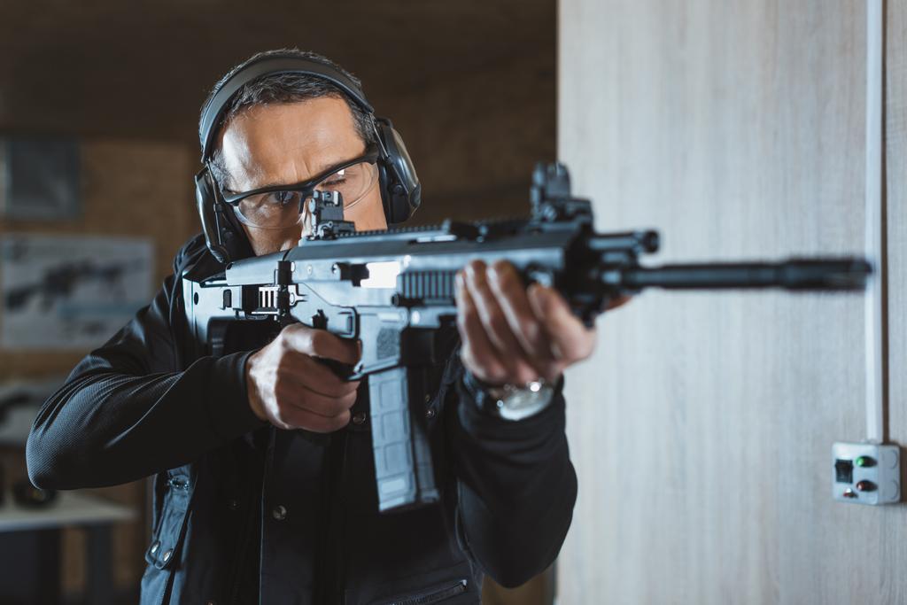 pohledný muž míření puškou v střelnice - Fotografie, Obrázek