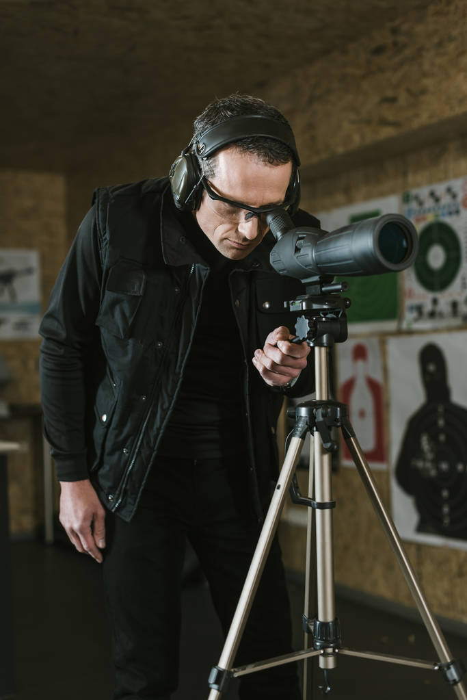 man looking through binoculars at remote target in shooting range - Photo, Image