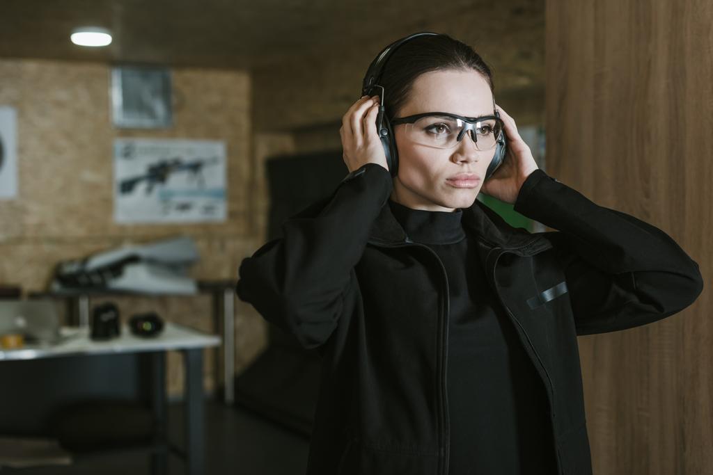 attraktives Mädchen mit Gehörschutz im Schießstand - Foto, Bild