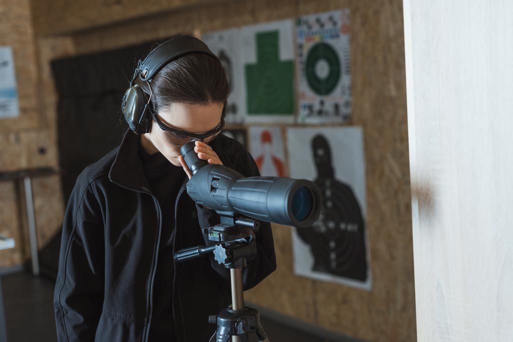 woman looking through binoculars in shooting range - Photo, Image