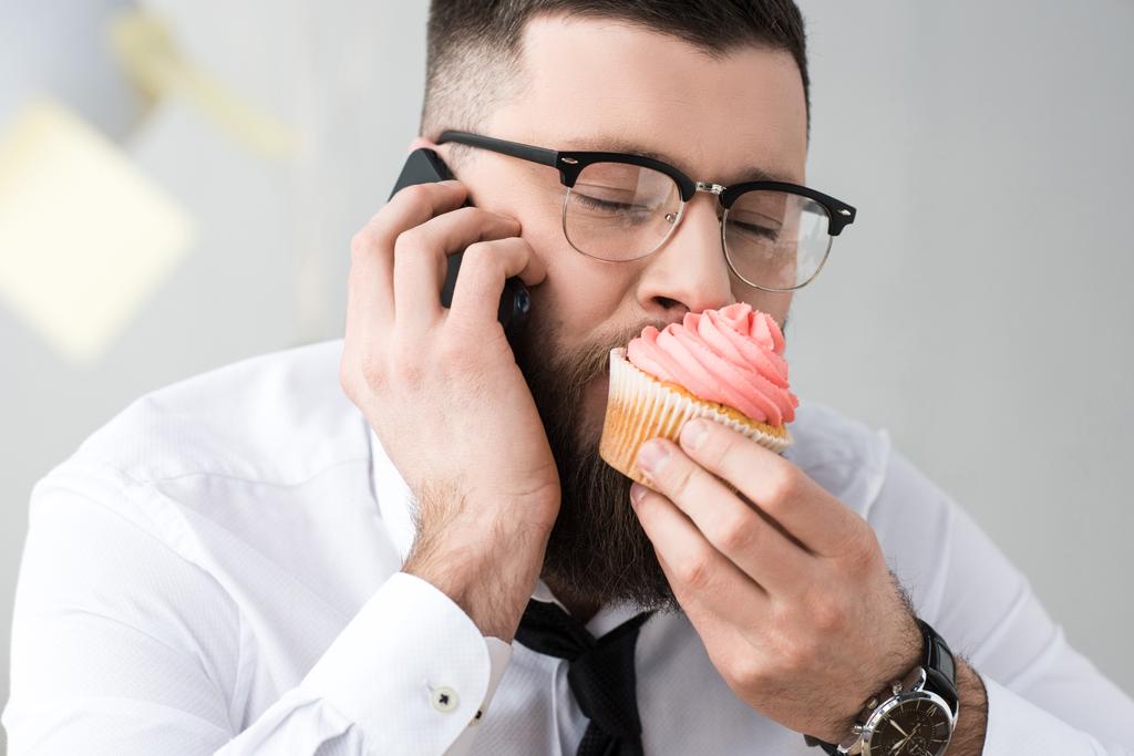 портрет бізнесмена, який їсть кекс під час розмови на смартфоні
 - Фото, зображення