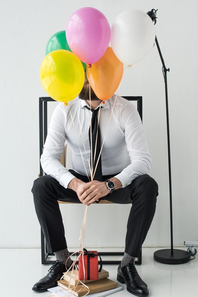 üzletember, a színes léggömbök ül a székre kitakart látképe - Fotó, kép