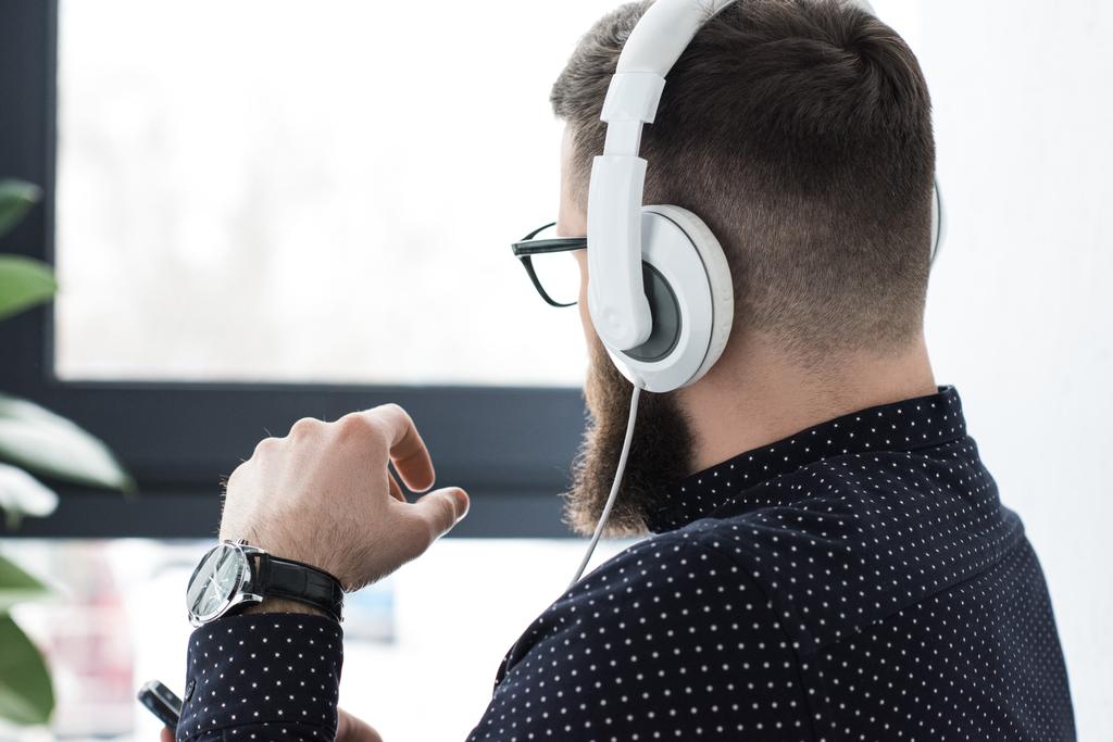 Teilbild eines Mannes mit Smartphone, der Musik im Kopfhörer hört - Foto, Bild