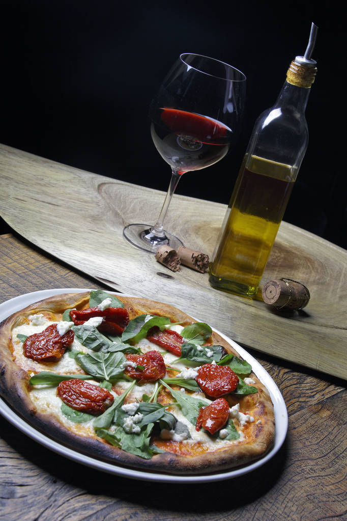 pizza met gedroogde tomaten en basilicum bladeren - Foto, afbeelding