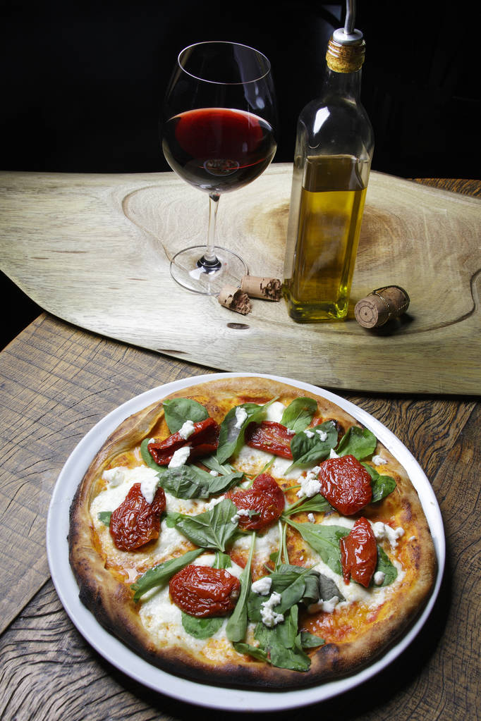 пицца с сушеными помидорами и листьями базилика
 - Фото, изображение