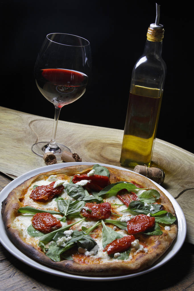 pizza met gedroogde tomaten en basilicum bladeren - Foto, afbeelding