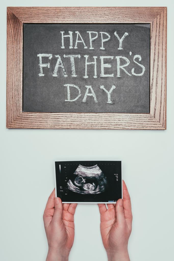 oříznuté záběr ženy s ultrazvukem v rukou a otců happy den tabule izolované Grey - Fotografie, Obrázek