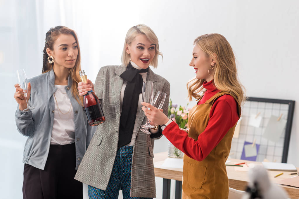 emocionados editores de revistas celebrando con champán en la oficina moderna
  - Foto, imagen