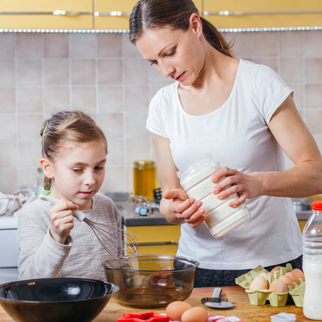 Äiti ja tytär keittiössä valmistelee taikinaa pizzaa varten
 - Valokuva, kuva