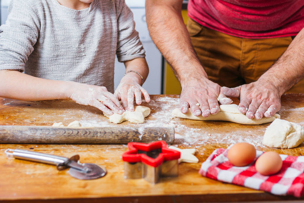маленька дівчинка з батьком робить тісто на домашній кухні
 - Фото, зображення