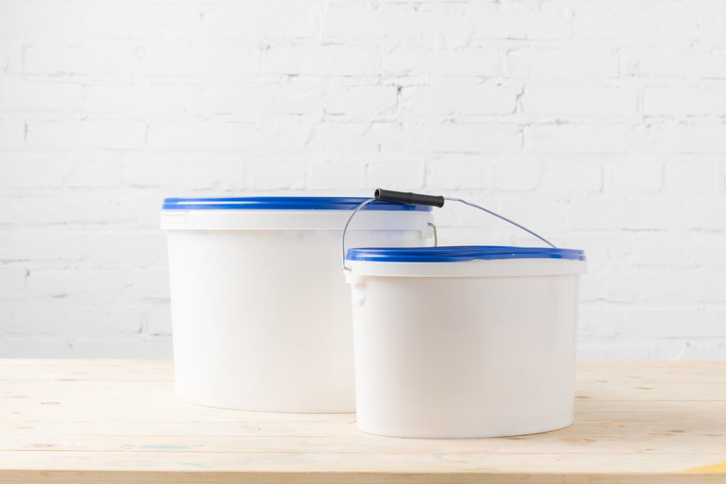 two plastic buckets with paints on wooden surface - Photo, Image