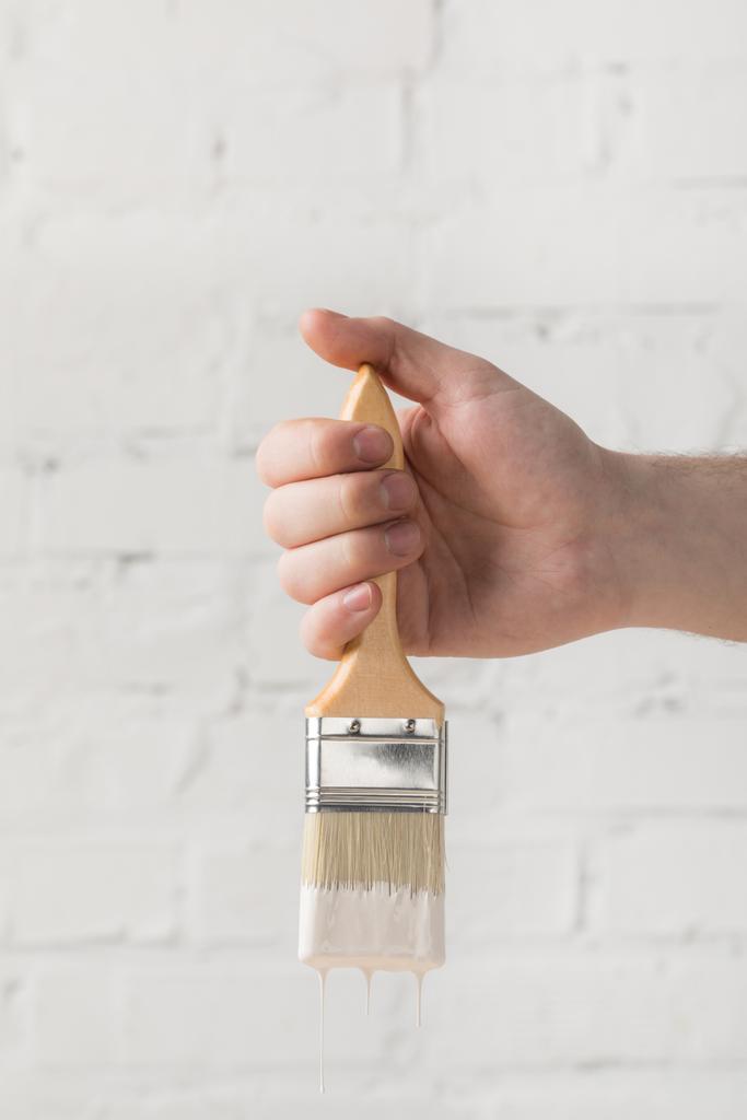 cropped image of man holding brush in white paint - Photo, Image