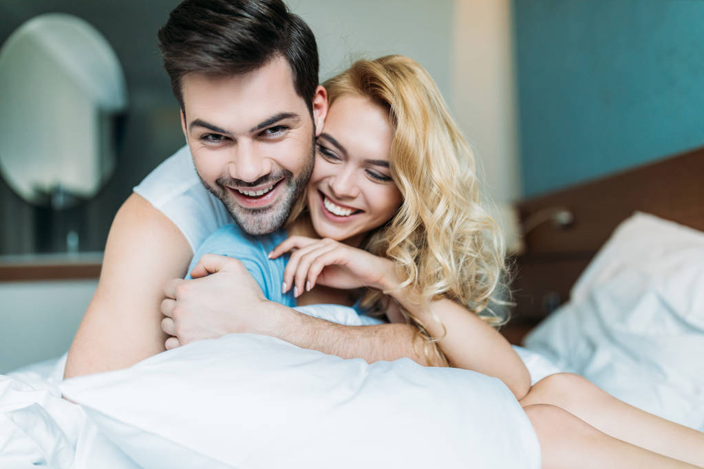 uśmiechający się para heteroseksualna, przytulanie na łóżku  - Zdjęcie, obraz