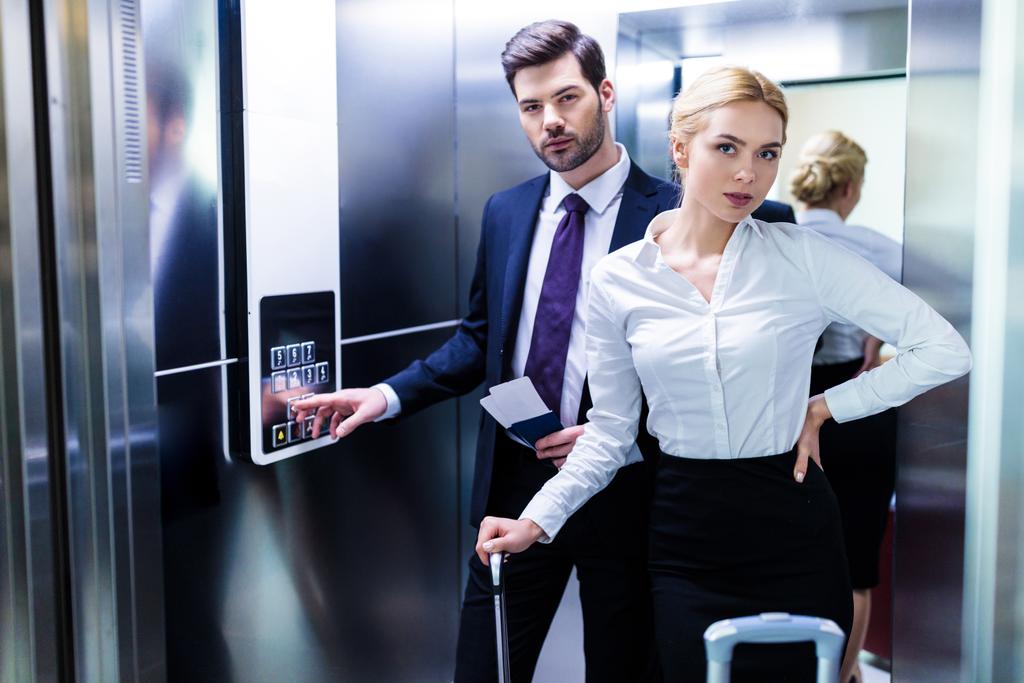 üzletember és üzletasszony-hotel lift látszó-on fényképezőgép - Fotó, kép