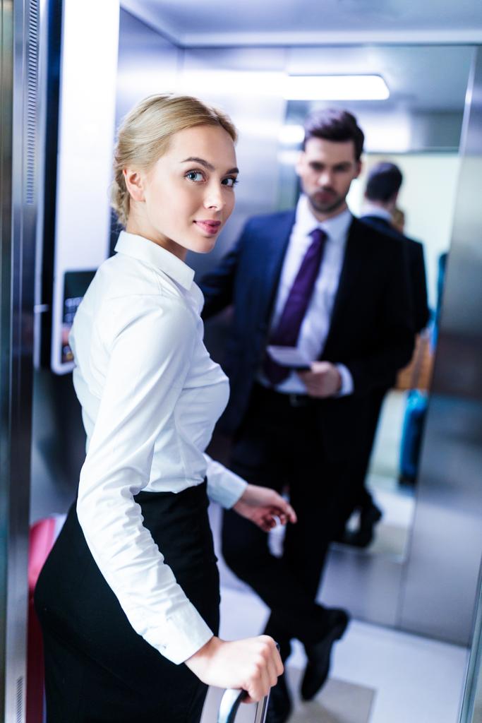бизнесмен и деловая женщина, входящие в лифт в отеле
 - Фото, изображение
